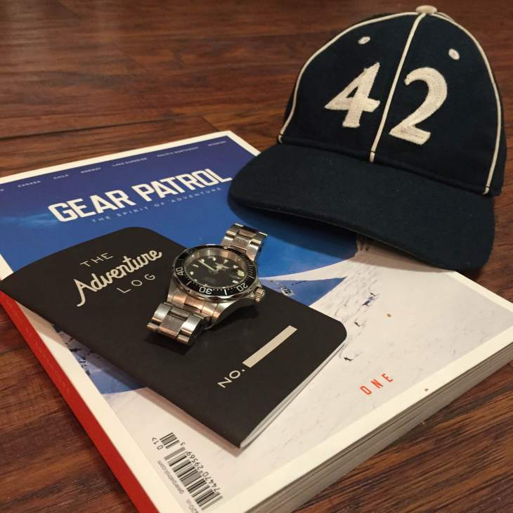 Travel gear for the road ahead. Vintage ballcap by Goorin Brothers. Adventure Log by Word Notebooks. Stainless steel dive watch by Invicta. Print magazine by Gear Patrol