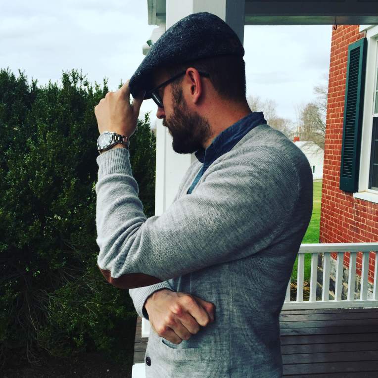 A flatcap -- best worn when the weather's cold. Elbow-patch cardigan by JACHS NY. Chambray shirt by GAP. Wool flatcap by Goorin Brothers. Stainless steel dive watch by Invicta. Glasses by Warby Parker.